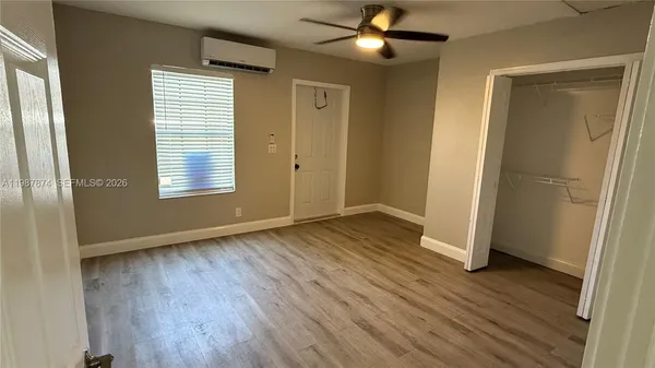 an empty room with wooden floor a ceiling fan and windows