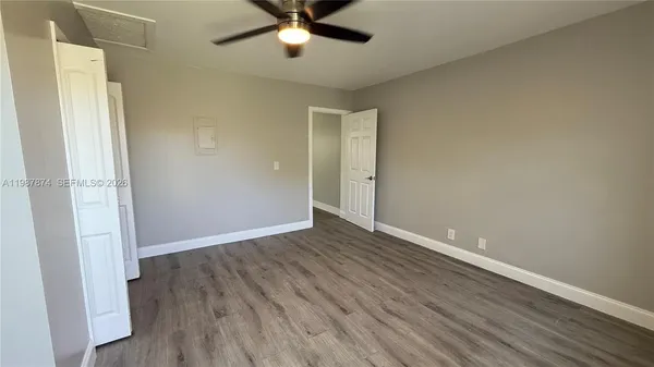 an empty room with wooden floor and a ceiling fan