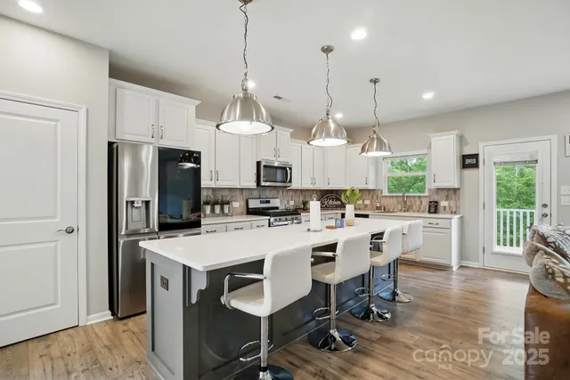 a kitchen with stainless steel appliances kitchen island granite countertop a table chairs and a refrigerator