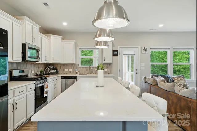a kitchen with stainless steel appliances a table chairs stove and white cabinets