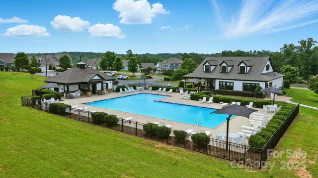 a view of a swimming pool with lawn chairs and a big yard
