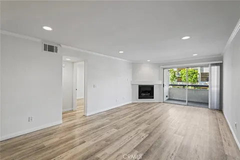 a view of an empty room with wooden floor fireplace and a window