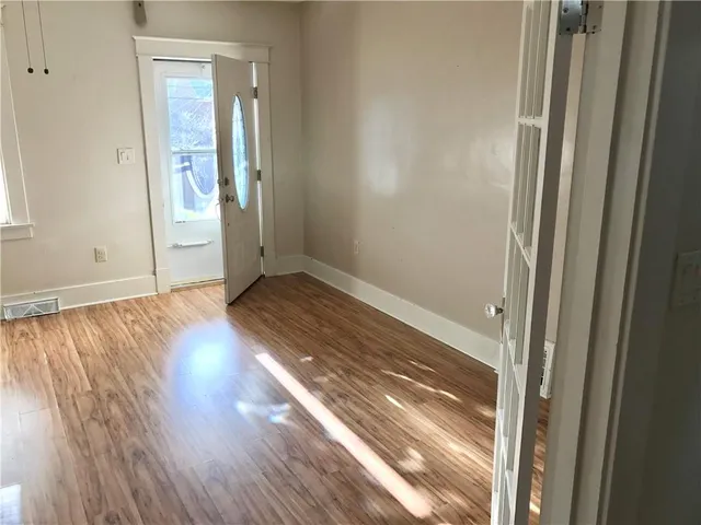an empty room with wooden floor and windows
