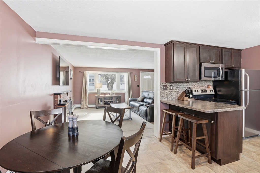 153 Summer Street Maynard, MA 01754 - Photo 12 of 26 a kitchen with granite countertop a table chairs stove and refrigerator