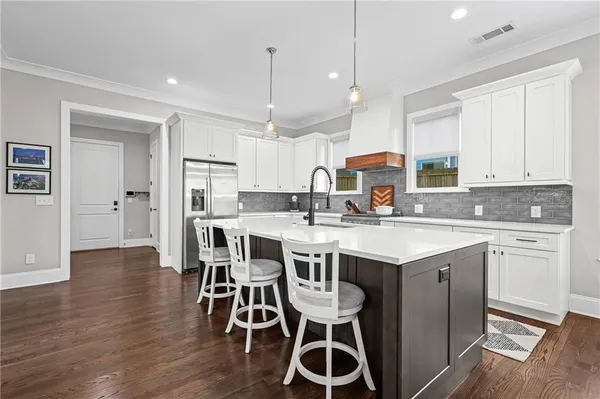 a kitchen with a dining table chairs wooden floor cabinets and appliances