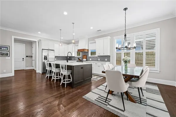 a dining room with stainless steel appliances kitchen island granite countertop a table chairs and a view of living room