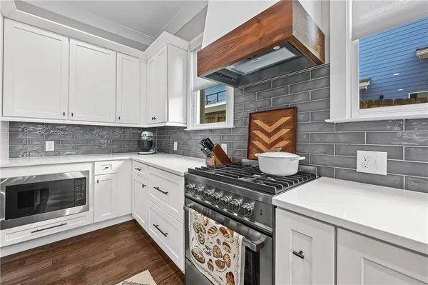 a kitchen with stainless steel appliances a stove and white cabinets