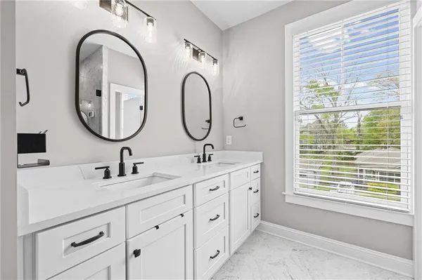 a bathroom with a double vanity sink a two mirror and a window