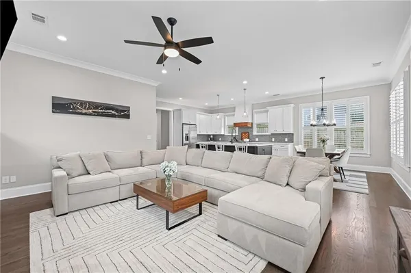 a living room with furniture kitchen view and a wooden floor