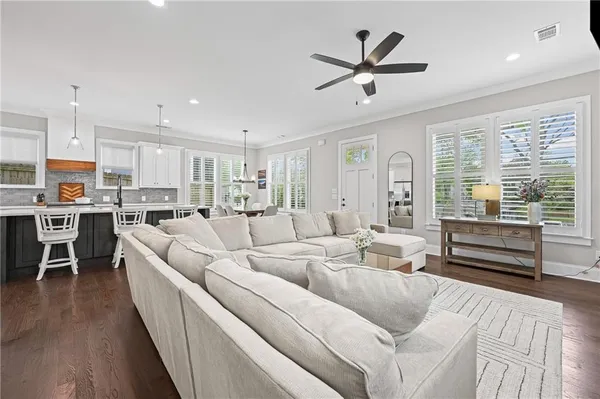 a living room with furniture kitchen area and a wooden floor