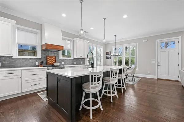a kitchen with a dining table chairs wooden floor cabinets appliances and a center island