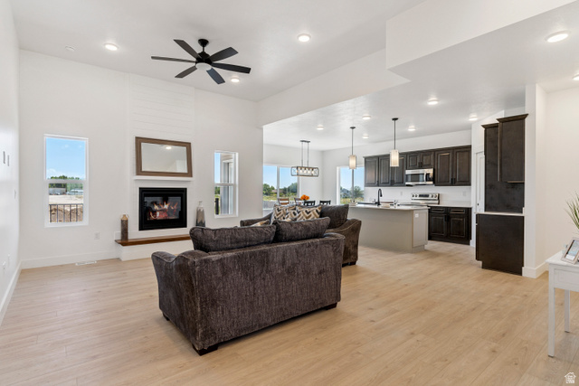 5777 West 4100 South Hooper, UT 84315 - Photo 4 of 41 Living area featuring a ceiling fan, light wood-style floors, a glass covered fireplace, and recessed lighting