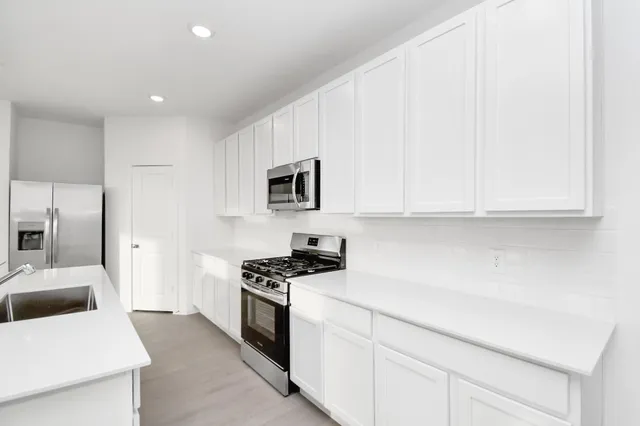 a kitchen with stainless steel appliances white cabinets and a sink