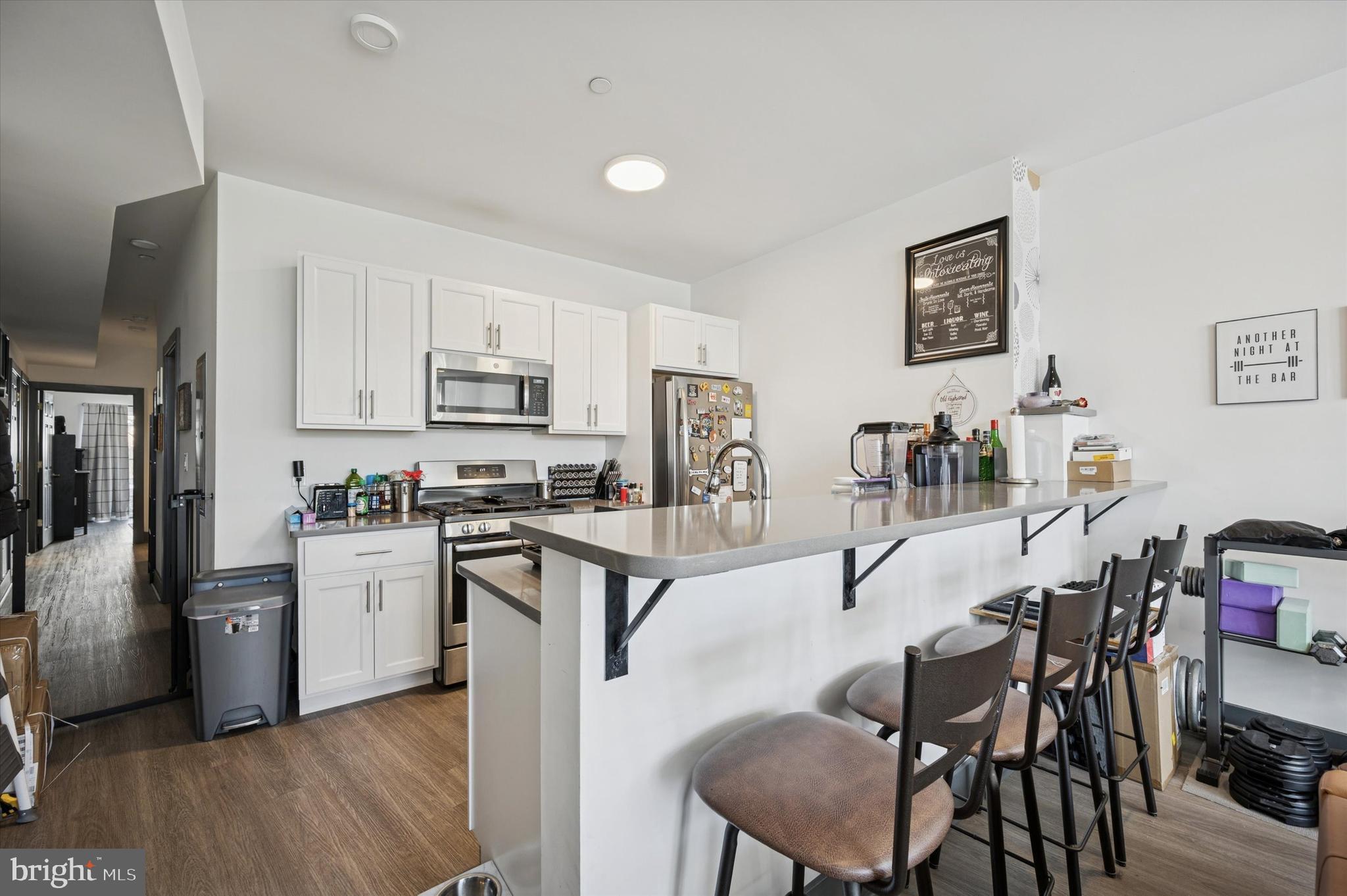 124-26 Levering Street, Unit 2A Philadelphia, PA 19127 - Photo 5 of 18 a kitchen with stainless steel appliances kitchen island granite countertop a table chairs cabinets and wooden floor