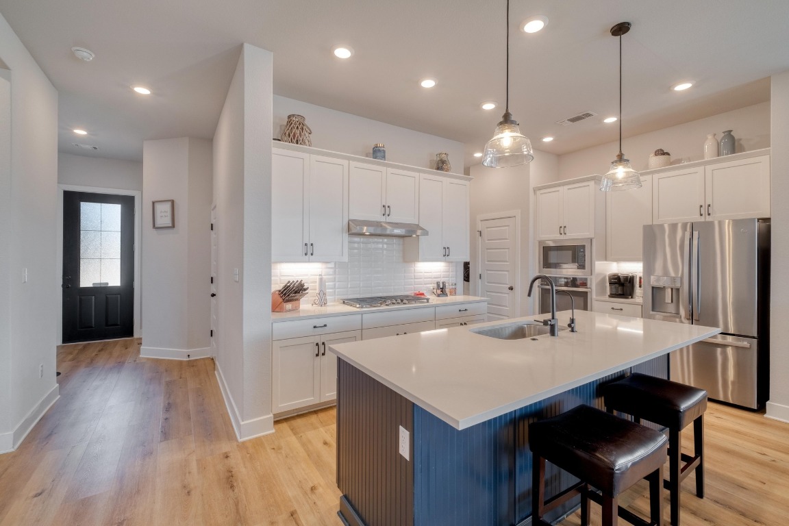 1113 Dog Iron Street Georgetown, TX 78633 - Photo 12 of 33 a kitchen with a sink a center island stainless steel appliances and cabinets