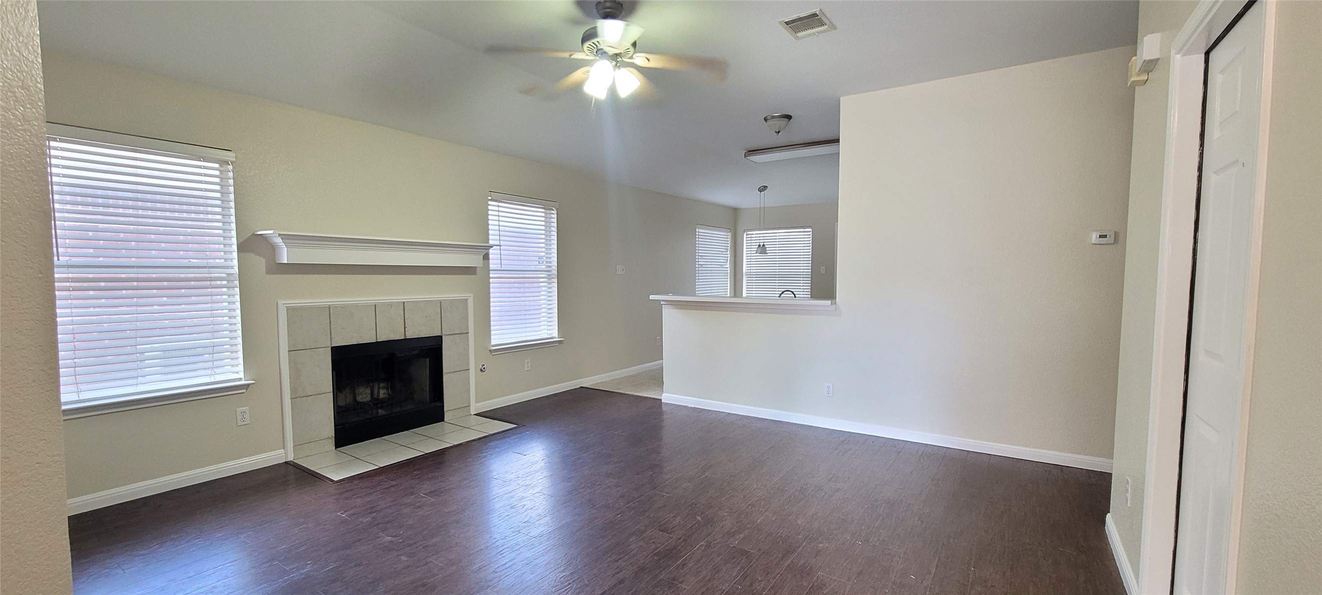 14612 Rumfeldt Street Austin, TX 78725 - Photo 2 of 9 an empty room with wooden floor a fireplace and windows