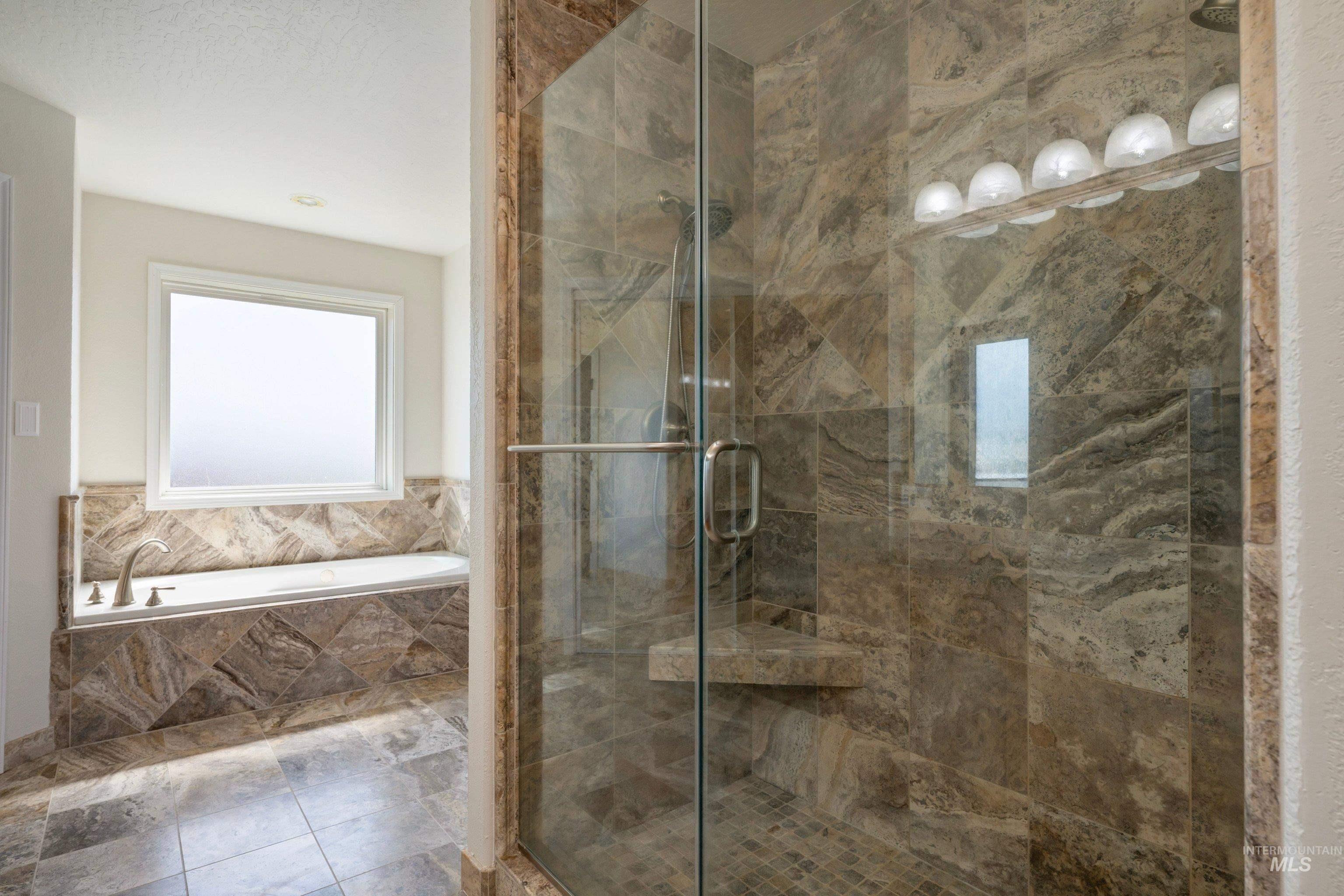 7657 Track Road Nampa, ID 83686 - Photo 25 of 49 Glass-enclosed shower with a built-in bench, complemented by a tiled surround and flooring