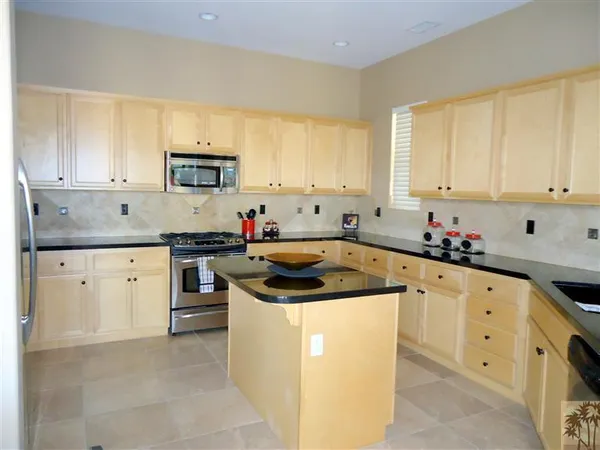 a kitchen with granite countertop a sink a stove and cabinets