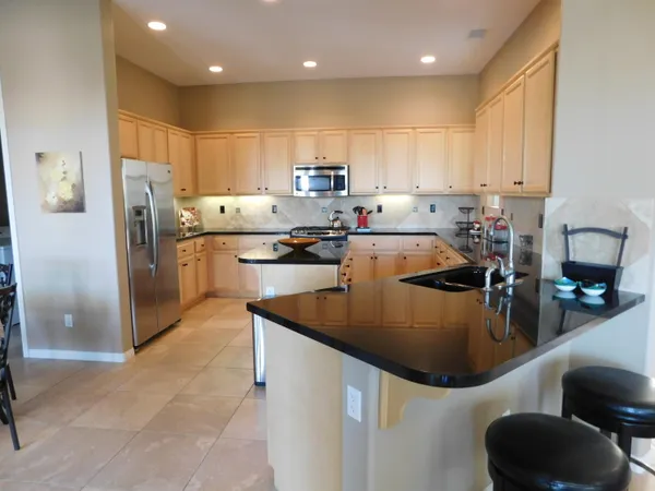 a kitchen with stainless steel appliances granite countertop a sink a refrigerator and a stove