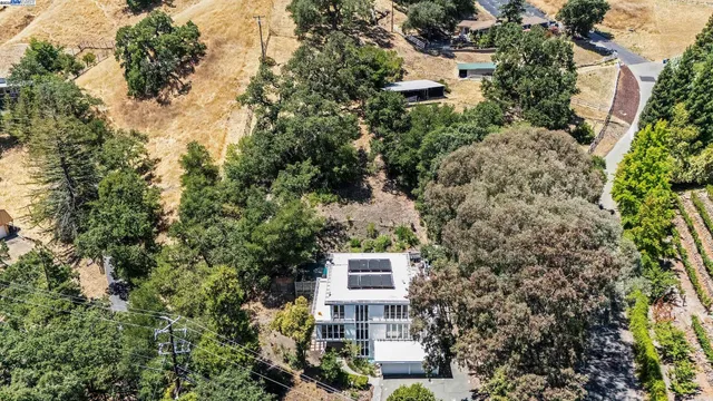 an aerial view of house with yard and trees all around