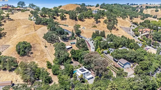 an aerial view of residential house with outdoor space and trees all around