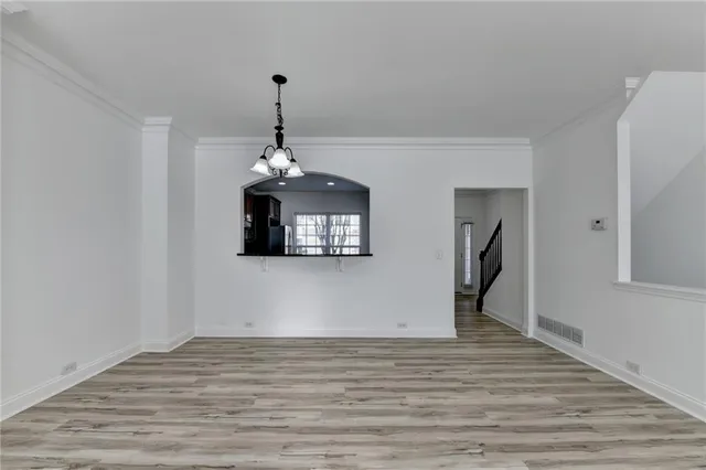 a room with wooden floor chandelier and windows