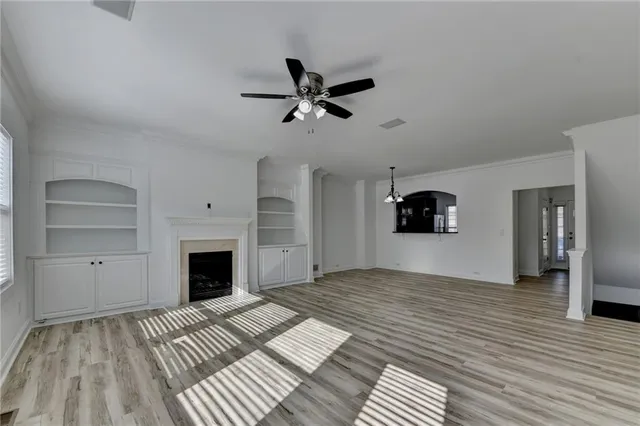 a view of a livingroom with a fireplace a ceiling fan and wooden floor