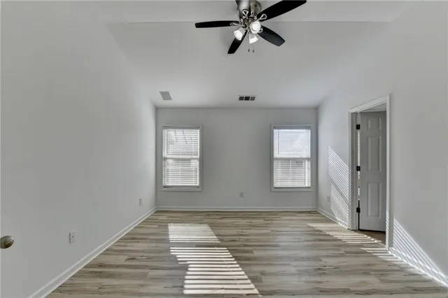 a view of an empty room with wooden floor and window