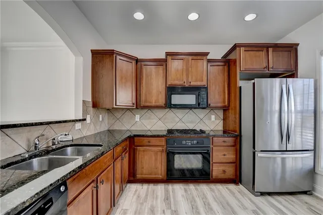a kitchen with stainless steel appliances granite countertop a refrigerator sink and stove