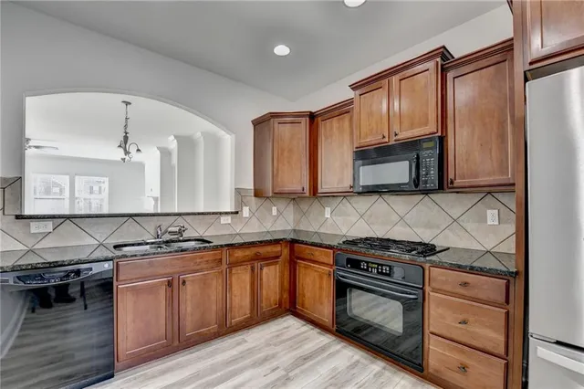 a kitchen with stainless steel appliances granite countertop a stove microwave and sink