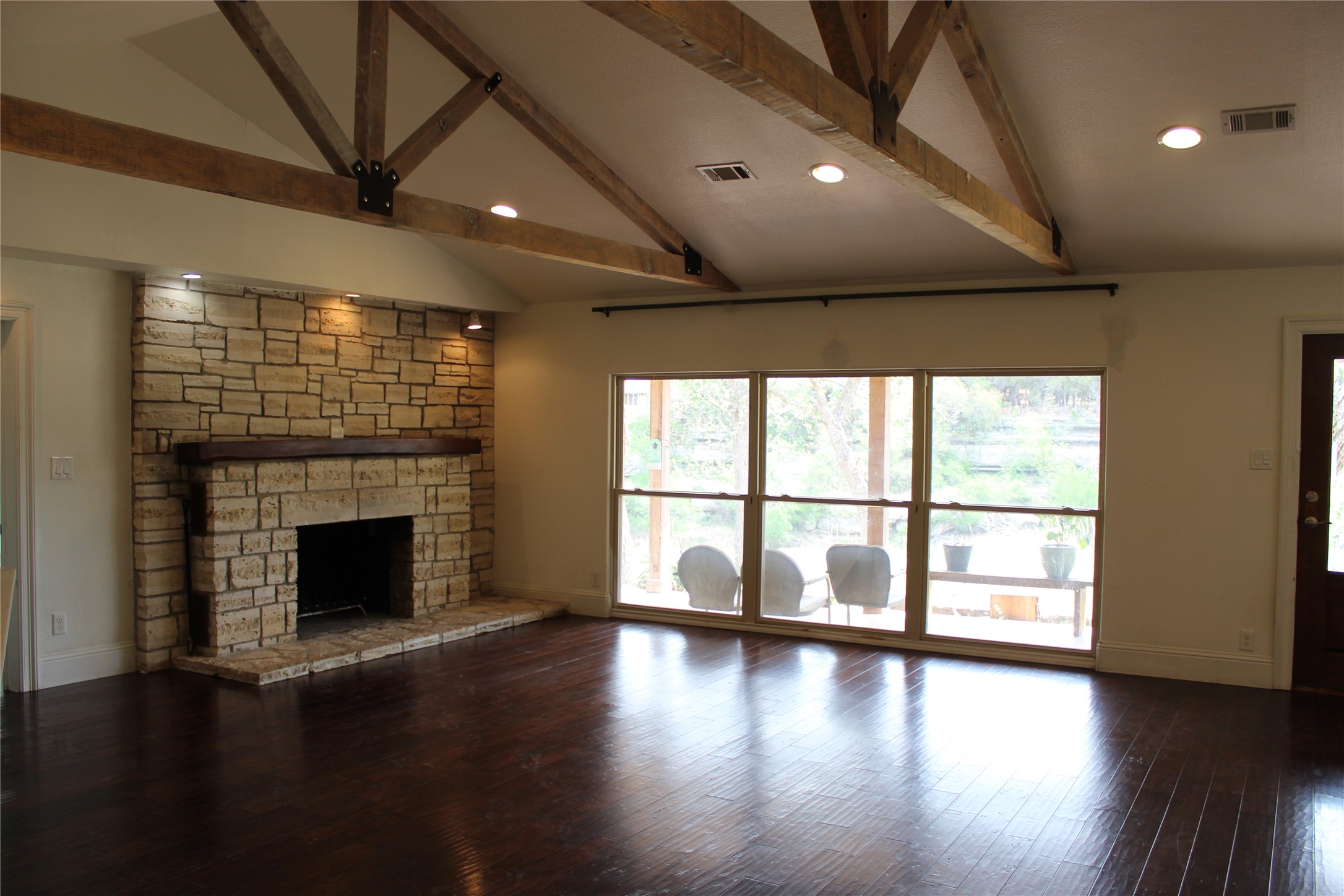 908 River Road Wimberley, TX 78676 - Photo 13 of 16 Unfurnished living room featuring dark wood-style floors, vaulted ceiling, a fireplace, and recessed lighting