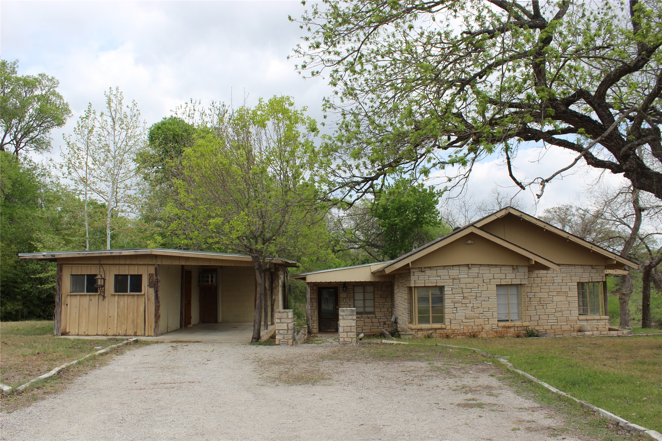 908 River Road Wimberley, TX 78676 - Photo 2 of 16 Ranch-style house with stone siding, gravel driveway, and board and batten siding