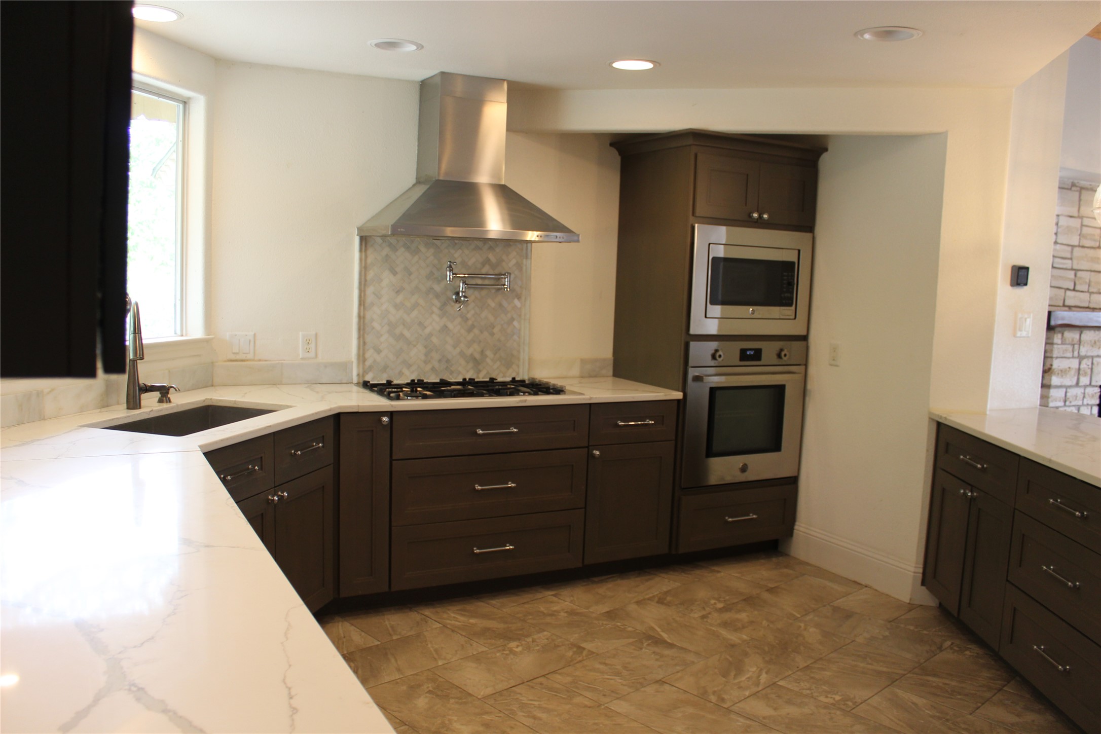 908 River Road Wimberley, TX 78676 - Photo 10 of 16 Kitchen featuring stainless steel appliances, backsplash, dark wood finish cabinetry, light stone countertops, and recessed lighting