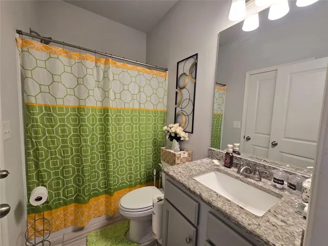 a bathroom with a granite countertop sink a toilet and a mirror