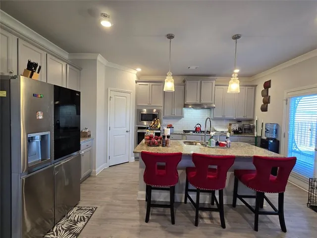 a kitchen with stainless steel appliances granite countertop a dining table chairs refrigerator and sink