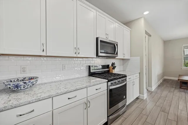 a kitchen with granite countertop white cabinets appliances and wooden floor