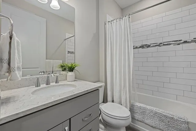 a bathroom with a granite countertop sink a toilet and shower