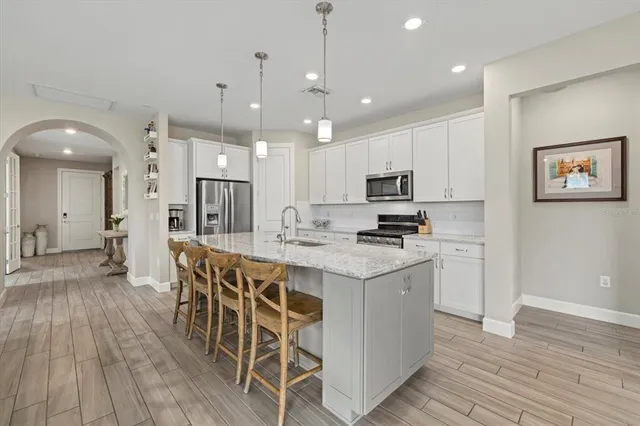 a kitchen with stainless steel appliances granite countertop a stove top oven a refrigerator a sink and a dining table with wooden floor