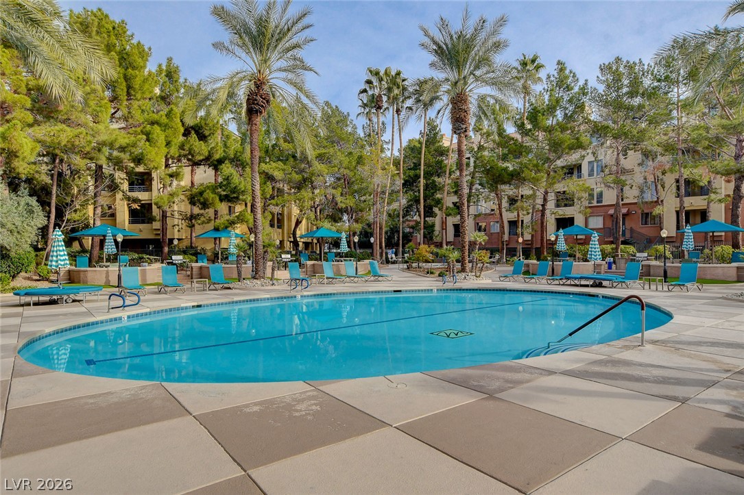 230 East Flamingo Road, Unit 106 Las Vegas, NV 89169 - Photo 45 of 66 Lush landscaping and towering palms surround a shimmering pool, creating a resort-like atmosphere.
