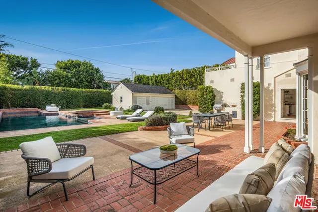 a view of a patio with couches table and chairs under an umbrella