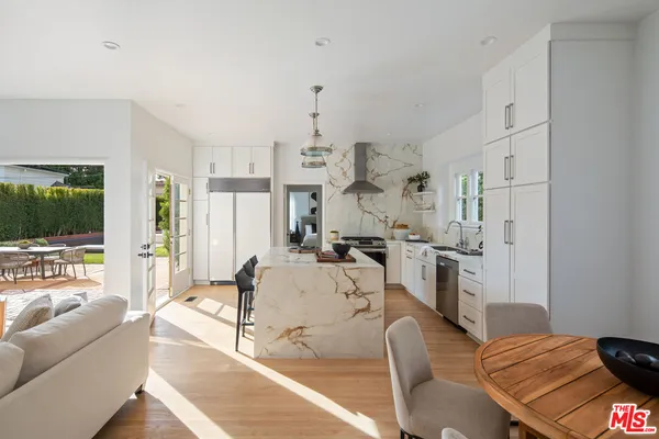 a living room with furniture kitchen view and a large window