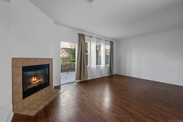 a view of an empty room with wooden floor fireplace and a window