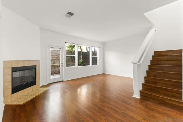 a view of an empty room with wooden floor fireplace and a window