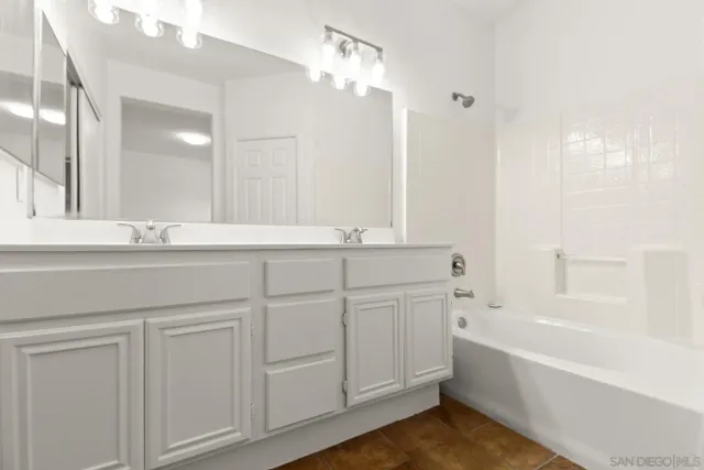 a bathroom with a bathtub a double vanity sink and a mirror