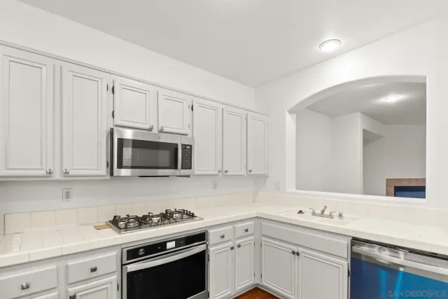 a kitchen with stainless steel appliances granite countertop grey cabinets a sink and dishwasher