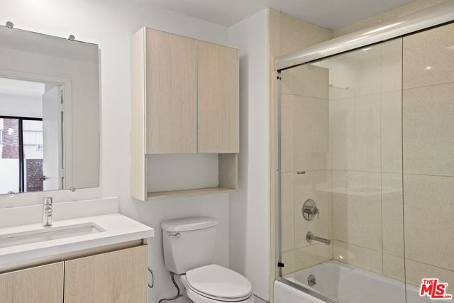 a bathroom with a shower sink vanity mirror and toilet