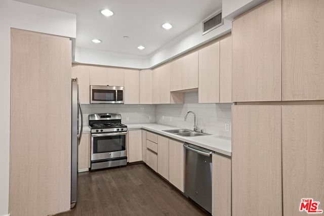 a kitchen with a sink white cabinets and stainless steel appliances
