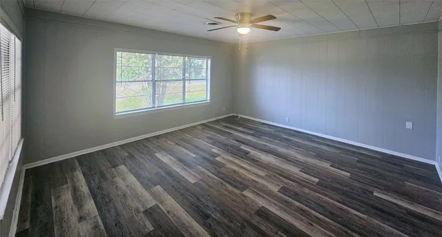 en empty room with wooden floor fan and window