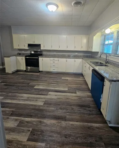 a large kitchen with wooden floor and stainless steel appliances