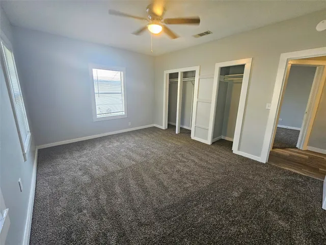 an empty room with windows and fan